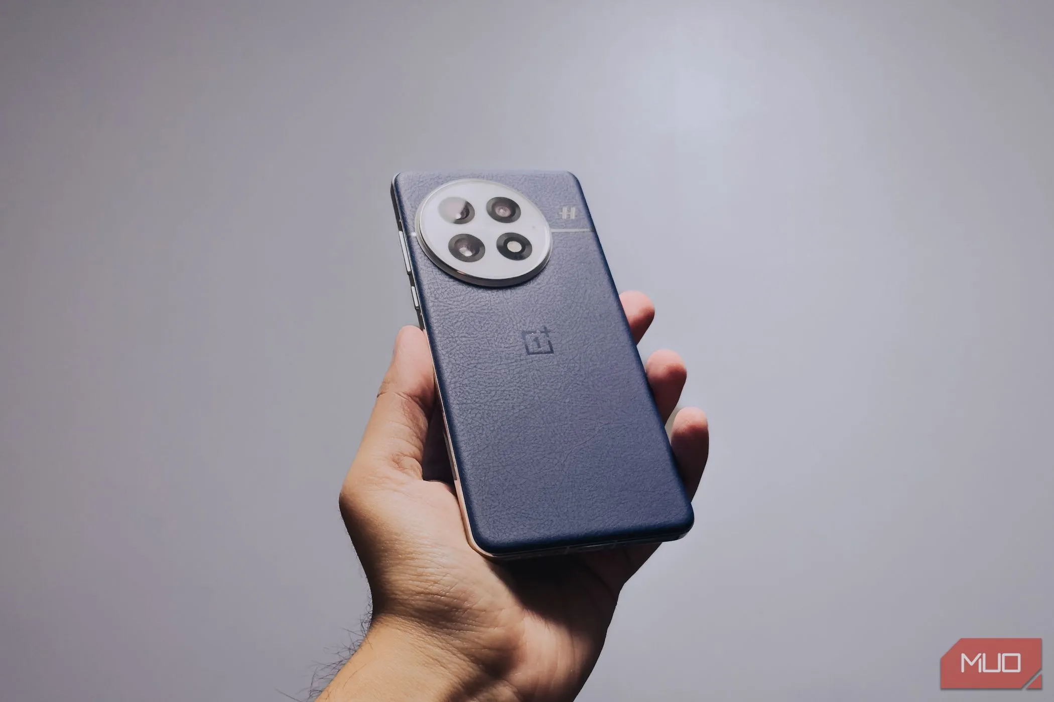 Cận cảnh điện thoại OnePlus 13 màu xanh Midnight Ocean đang được cầm trên tay, cho thấy thiết kế cải thiện độ bám.