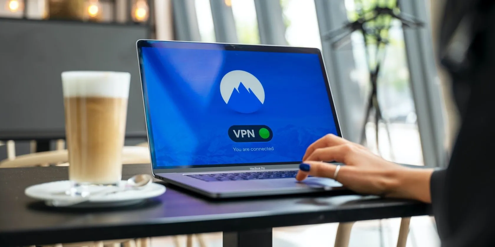 Người dùng đang sử dụng VPN trên máy tính xách tay trong quán cà phê, minh họa cho sự tiện lợi nhưng cũng tiềm ẩn phức tạp của VPN