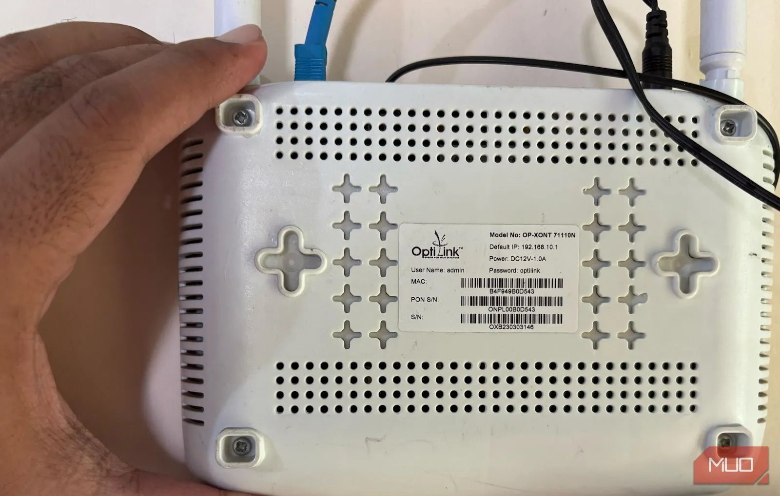 Bàn tay đang cầm và chỉ vào mặt sau của bộ định tuyến Wi-Fi