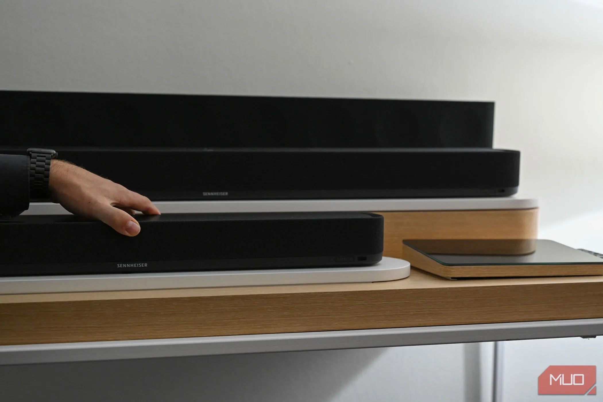 Bàn tay đặt trên loa soundbar Sennheiser Ambeo Soundbar Mini màu đen.