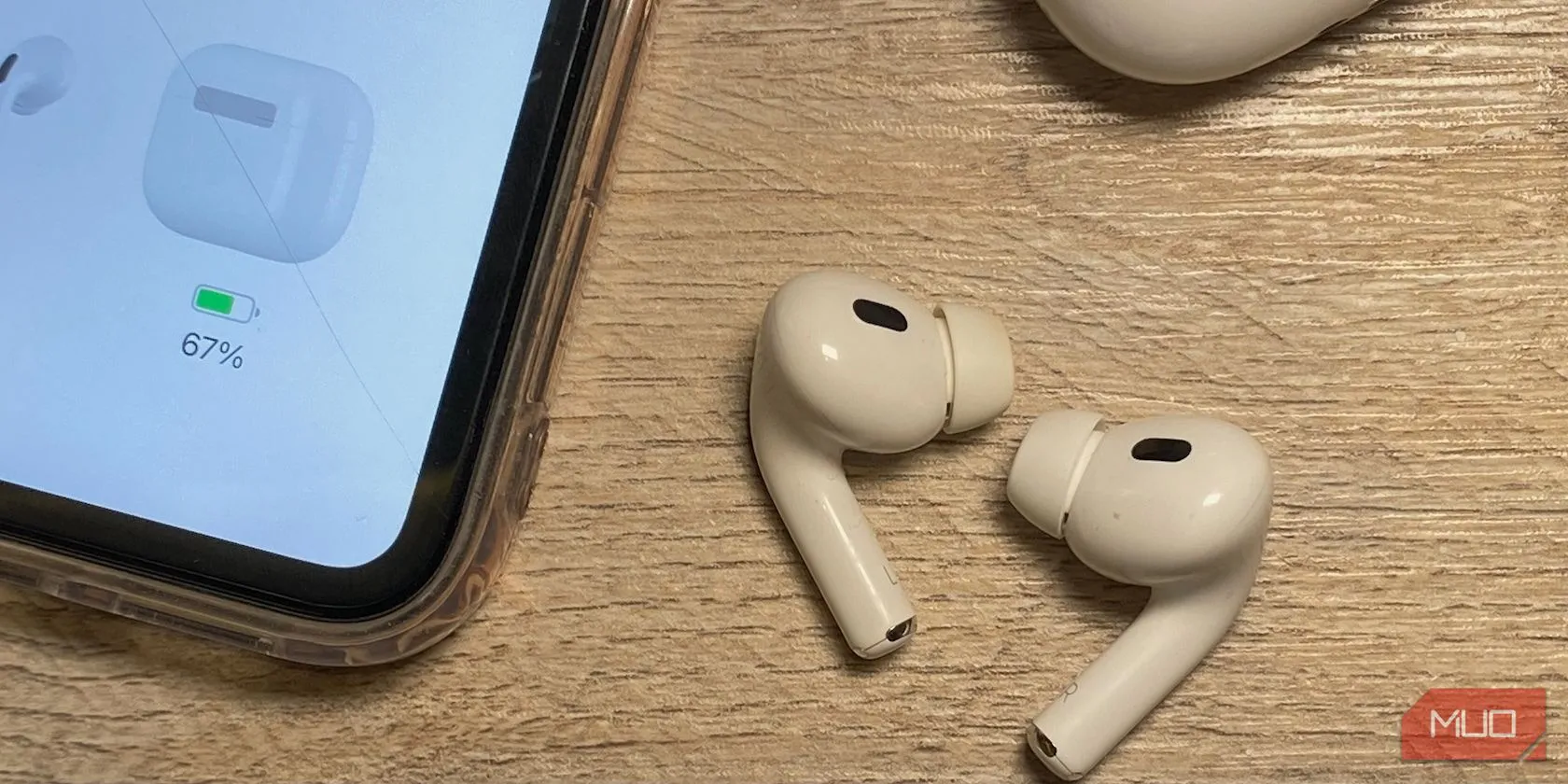 Các mẫu tai nghe AirPods nhét tai với chiều dài thân khác nhau đặt trên bàn gỗ cạnh iPhone, minh họa sự khác biệt giữa các thế hệ.