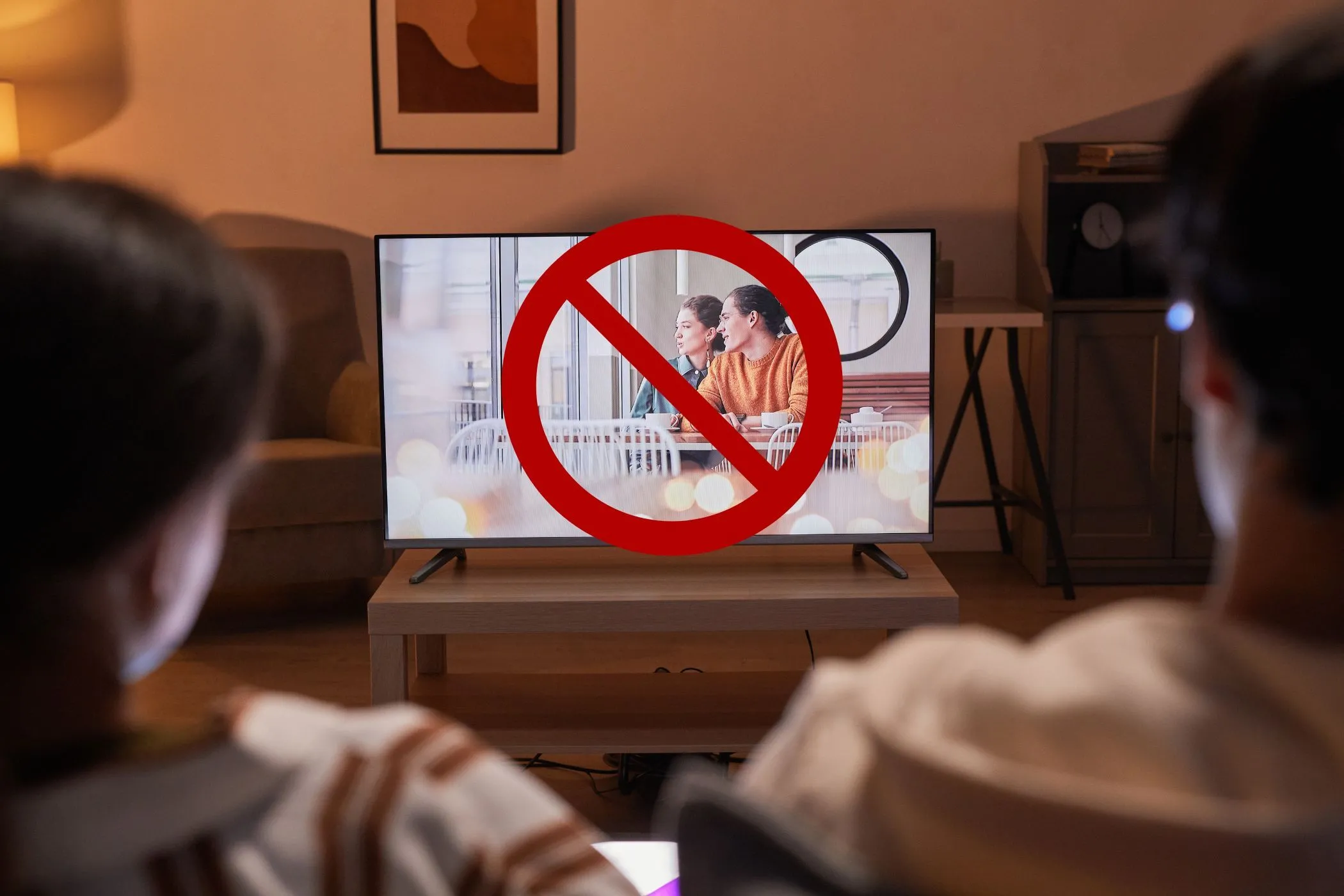 Cặp đôi xem TV với biểu tượng gạch chéo trên màn hình, ám chỉ việc tắt các tính năng theo dõi và đề xuất AI để bảo vệ quyền riêng tư trên Smart TV