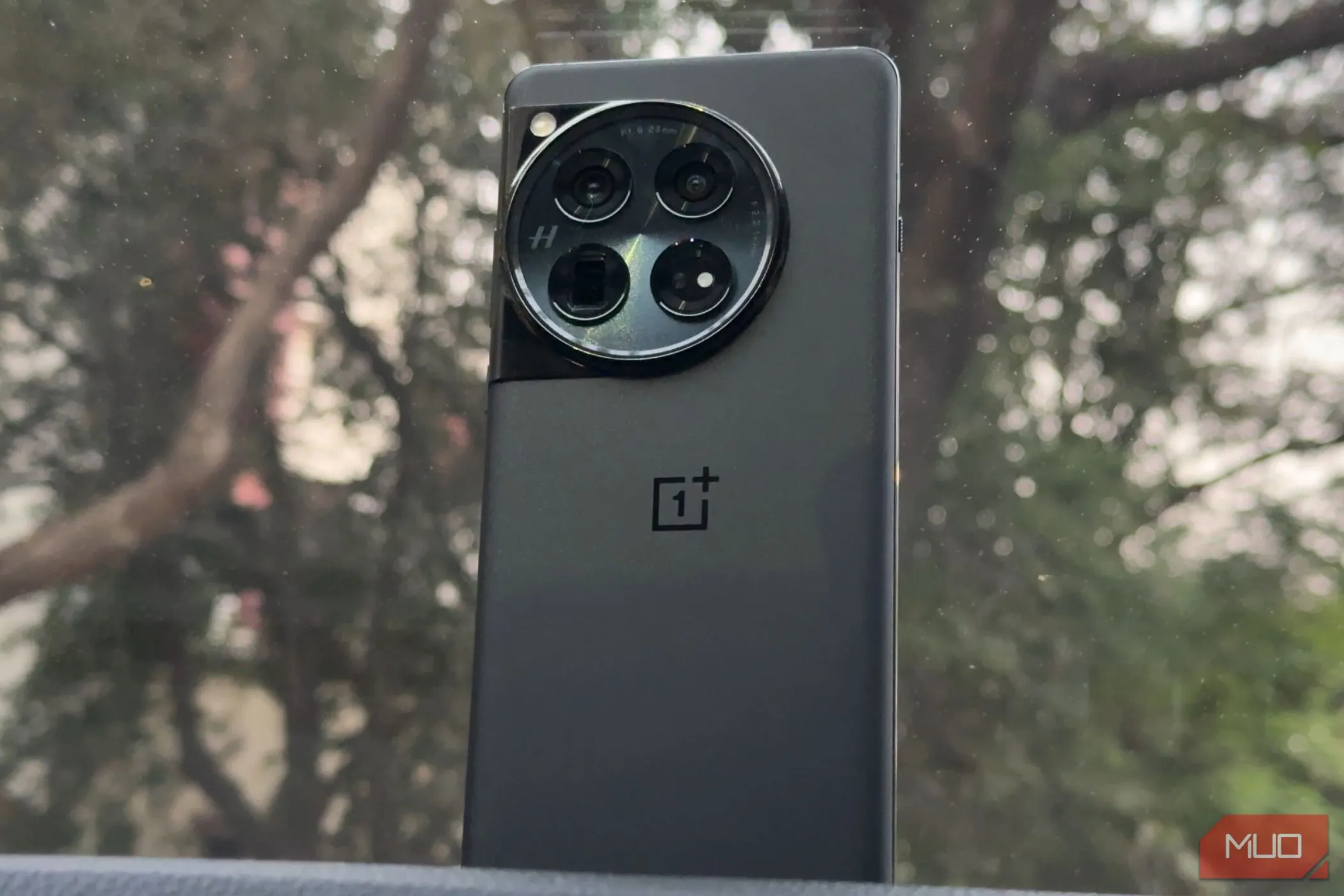 Điện thoại OnePlus 12 màu đen đặt trên bảng điều khiển ô tô, thể hiện vẻ ngoài sang trọng