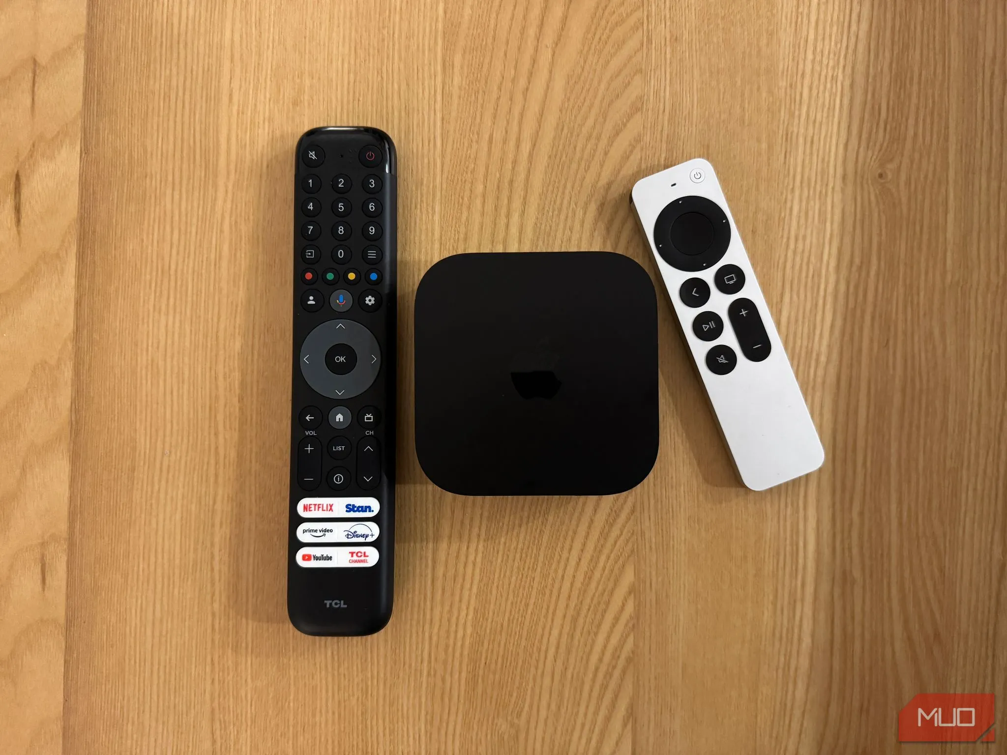 Điều khiển Siri Remote của Apple TV 4K được đặt cạnh remote TV truyền thống, làm nổi bật sự khác biệt về thiết kế và chất liệu cao cấp.
