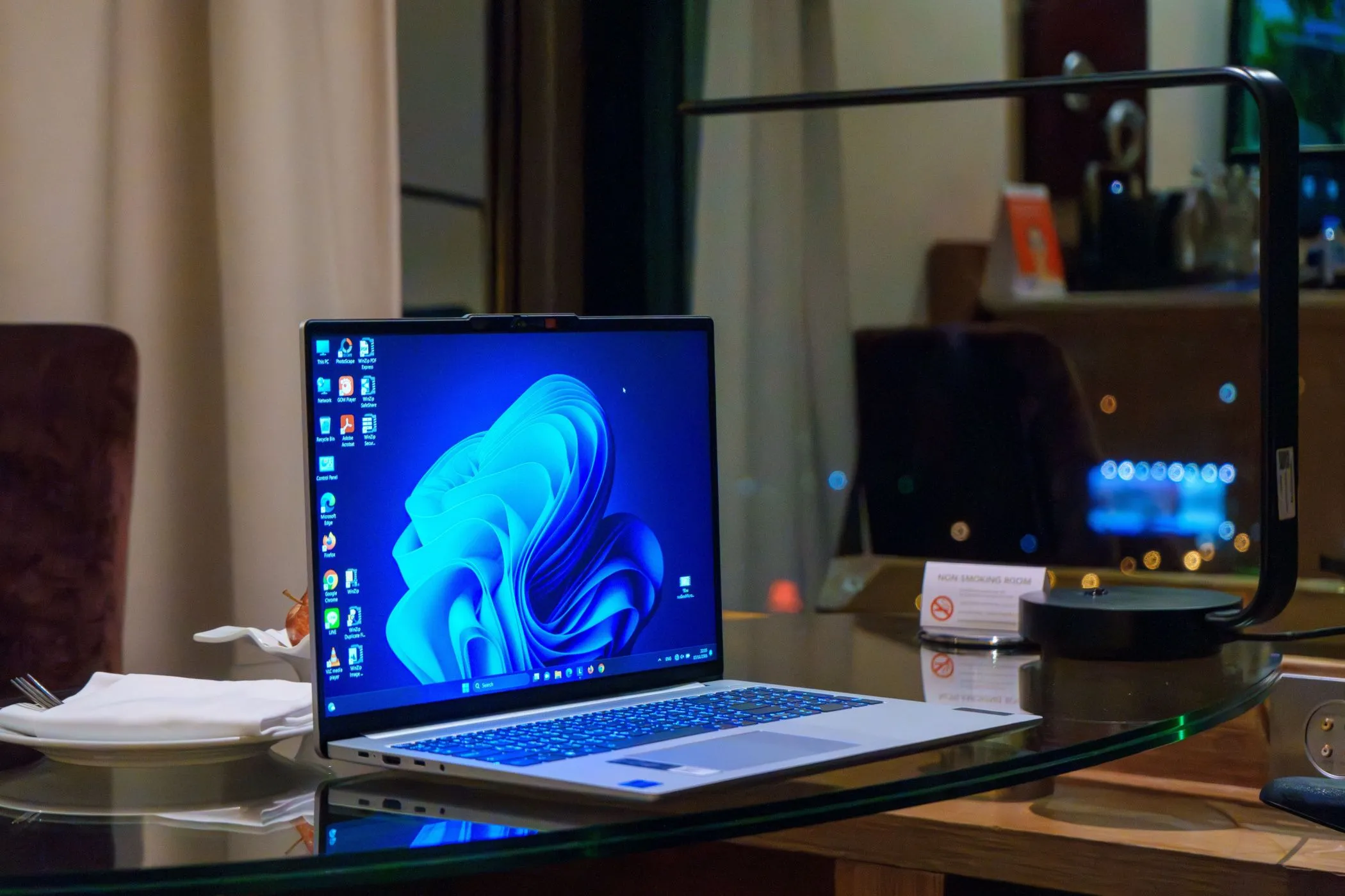 Hình ảnh máy tính xách tay Windows trên bàn kính với các biểu tượng desktop, đại diện cho rủi ro bảo mật khi tải game hoặc phần mềm từ các nguồn không đáng tin cậy.