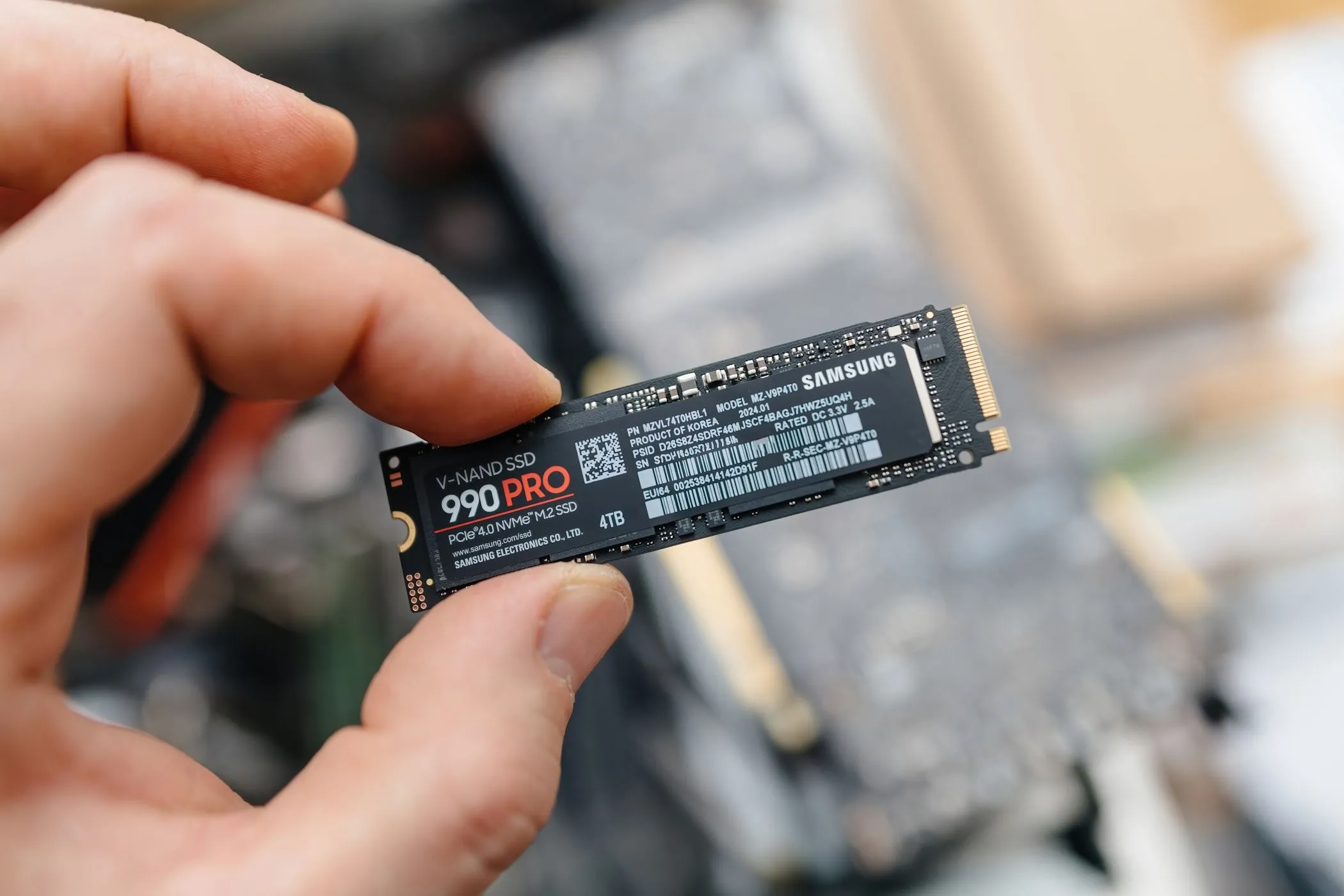 Hình ảnh một người đàn ông đang cầm trên tay ổ cứng SSD NVMe Samsung 990 Pro, minh họa cho các lựa chọn ổ cứng hiệu năng cao nhưng không nhất thiết phải đắt đỏ.