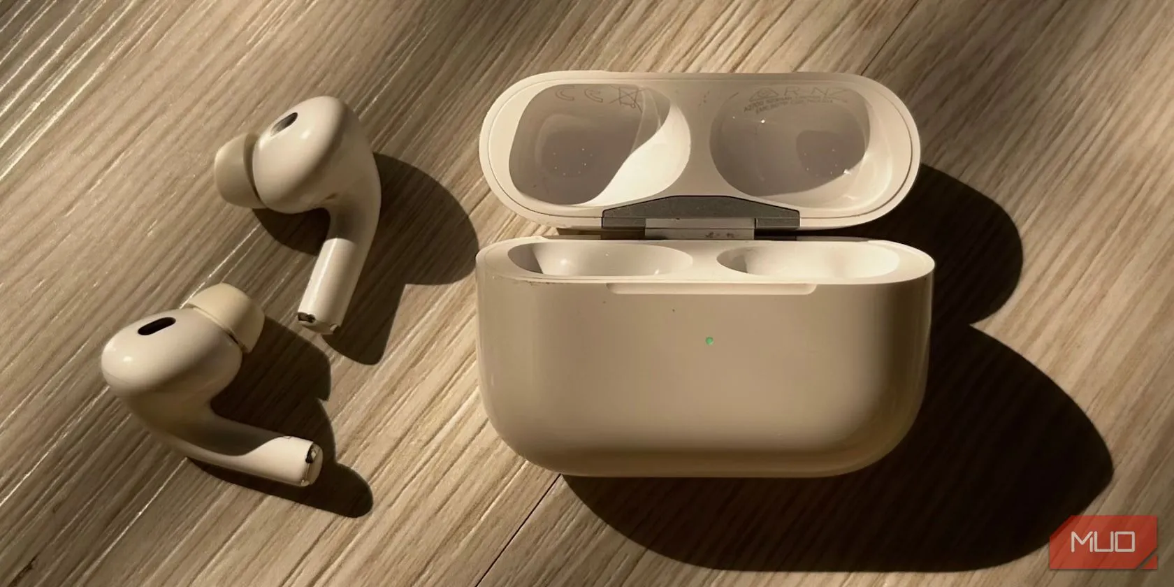 Hộp sạc AirPods với đèn trạng thái màu xanh lá cây, điển hình cho các mẫu AirPods thế hệ 3 hoặc AirPods Pro với thiết kế hình chữ nhật ngang.