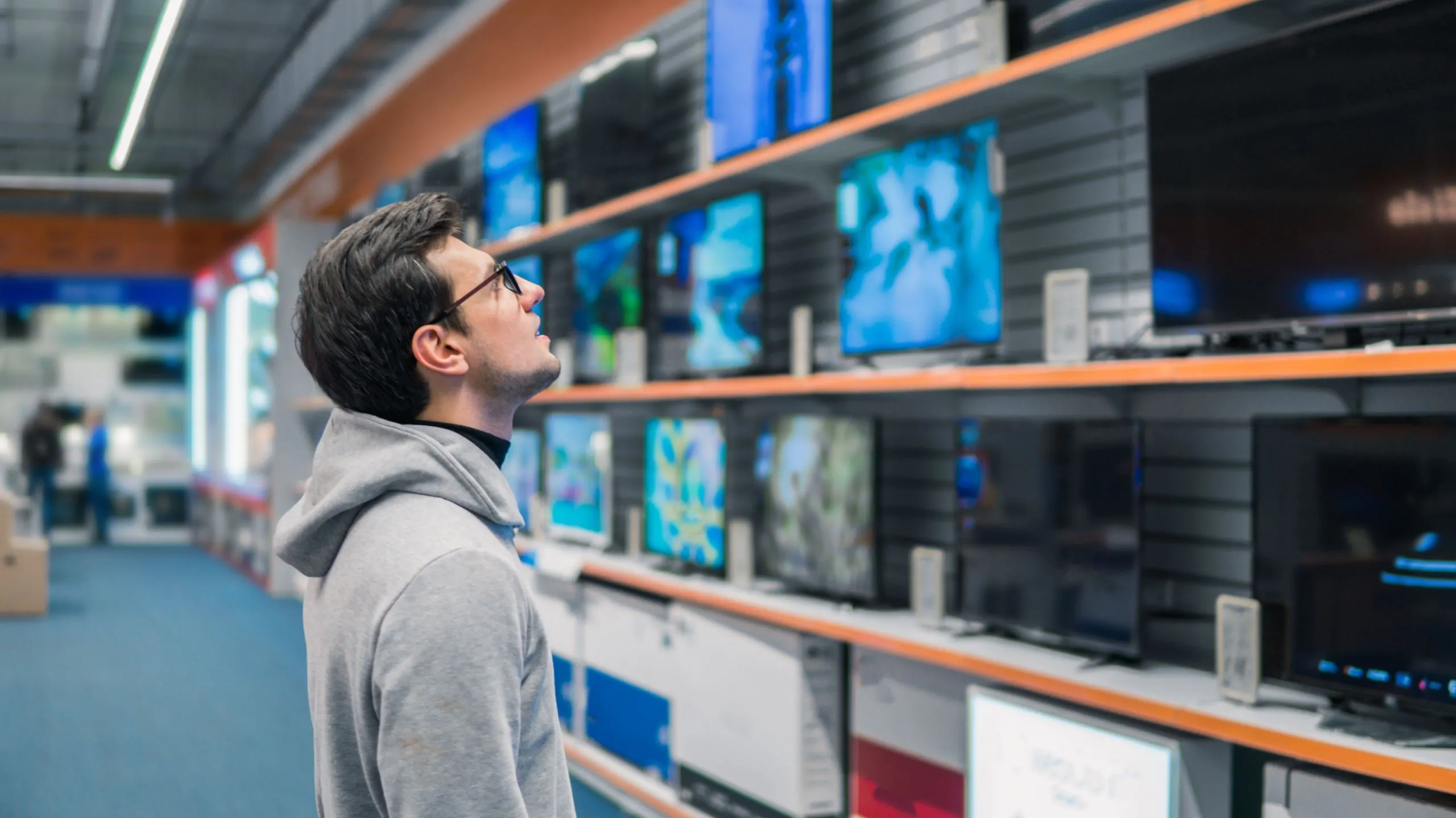 Khách hàng đang xem xét các mẫu TV thông minh QLED 4K đa dạng trên kệ tại cửa hàng điện tử