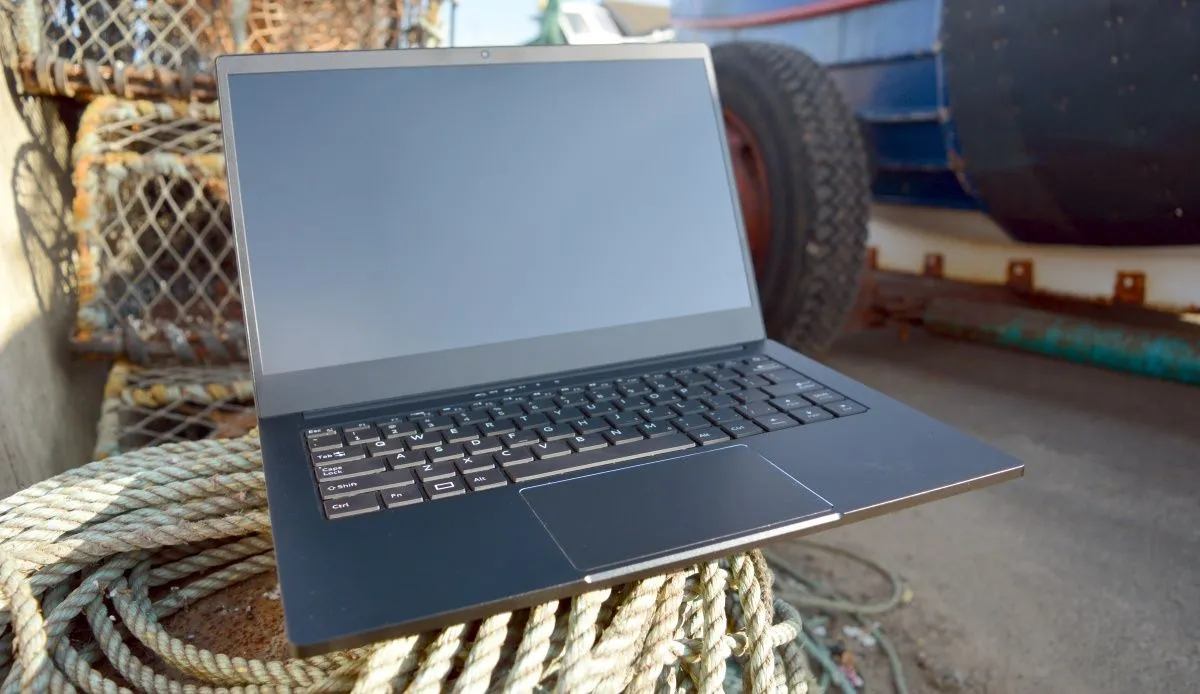 Laptop Librem màu đen bạc đặt trên mặt đất, gần một chiếc xe tải nhỏ màu đỏ
