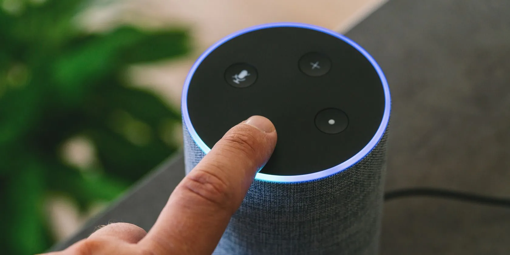 Loa thông minh Amazon Echo màu đen đặt trên bàn, gần một người đang thao tác, thể hiện sự tiện lợi trong giải trí cá nhân