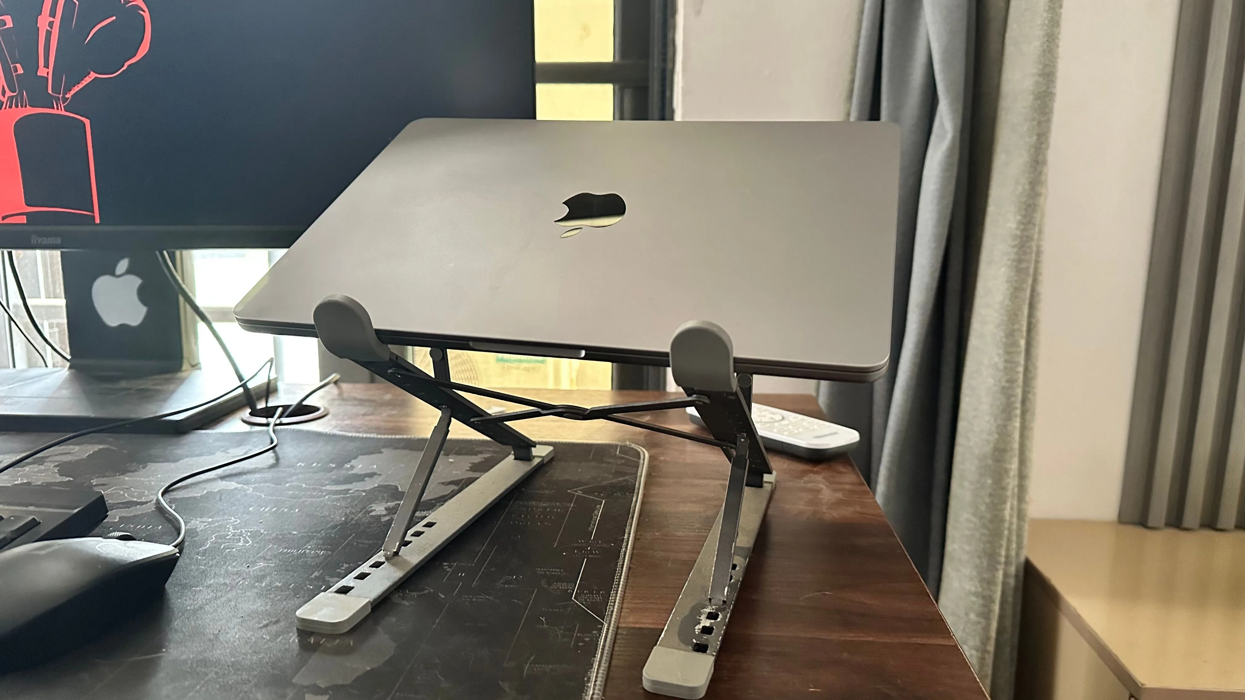 MacBook đặt trên đế tản nhiệt bên cạnh màn hình ngoài, minh họa cách tối ưu tản nhiệt khi sử dụng màn hình rời