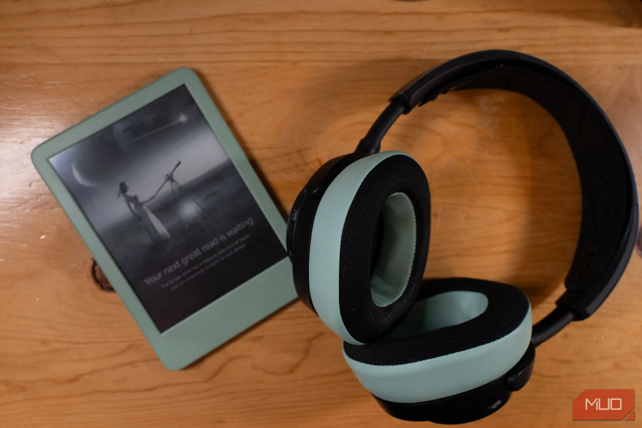 máy đọc sách Kindle 2024 màu xanh matcha và tai nghe cùng màu đang kết nối không dây, thể hiện tính tương thích giữa các thiết bị.
