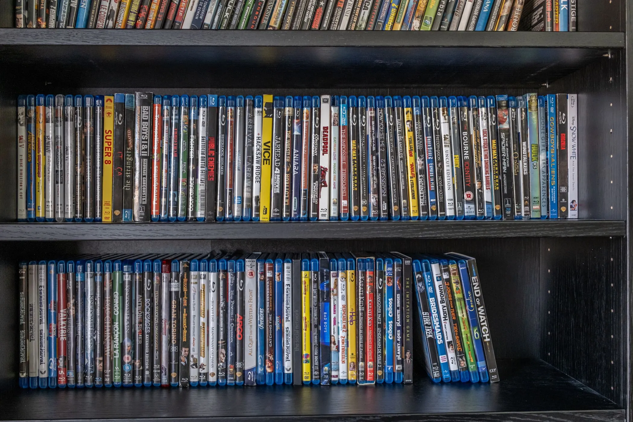 Một bộ sưu tập đĩa Blu-ray được sắp xếp gọn gàng trên kệ sách gỗ, thể hiện sự đa dạng của các tựa phim