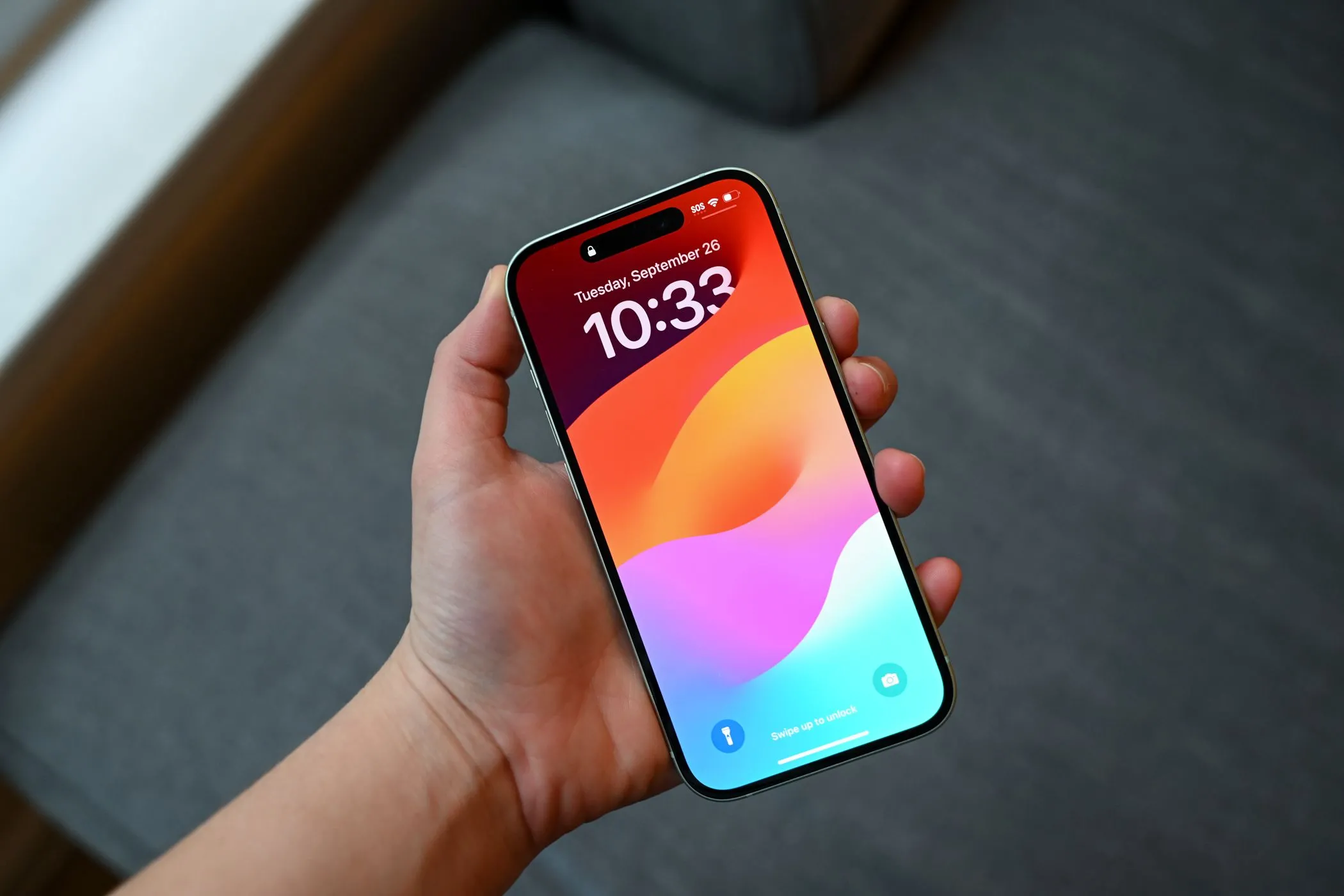 Một người đang cầm chiếc iPhone 15 với màn hình khóa, cho thấy hiệu quả của miếng dán chống nhìn trộm trong việc che giấu vết xước