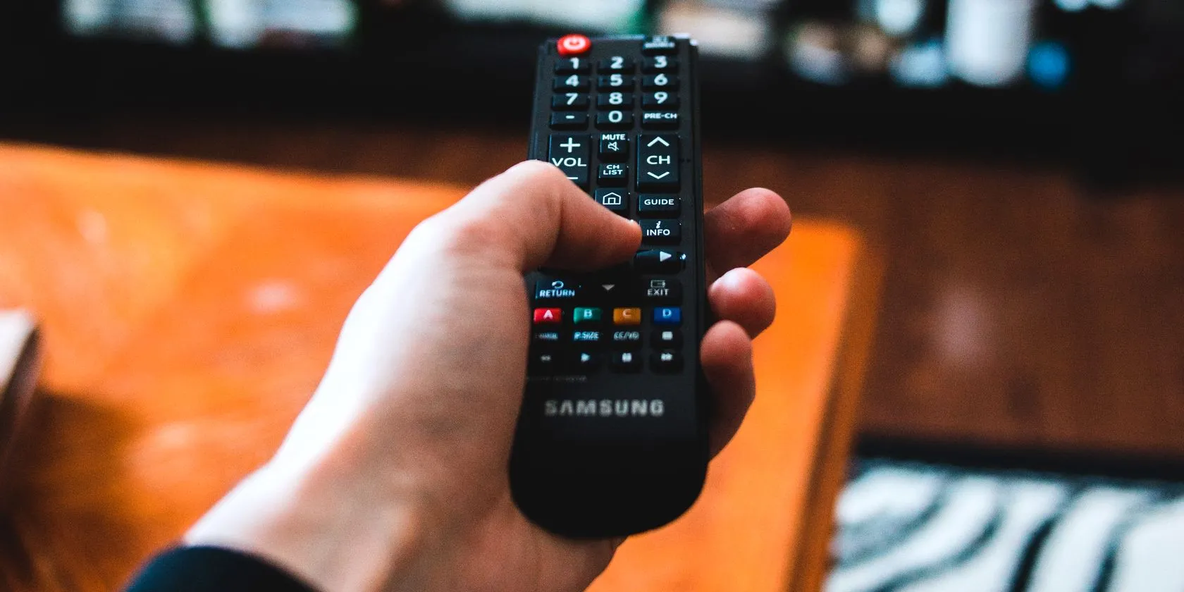 Người dùng đang thao tác thay đổi kênh TV với điều khiển từ xa, tương tự khả năng của IR Blaster trên điện thoại