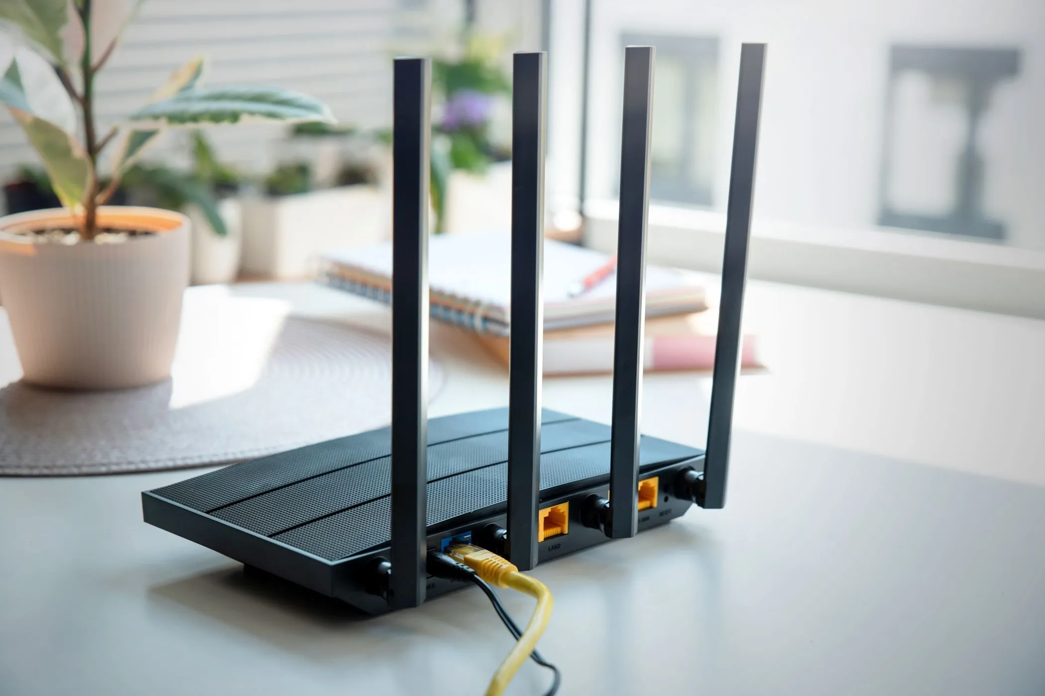 Router Wi-Fi với bốn ăng-ten đặt trên bàn, tượng trưng cho giải pháp router phụ để tạo mạng khách an toàn.
