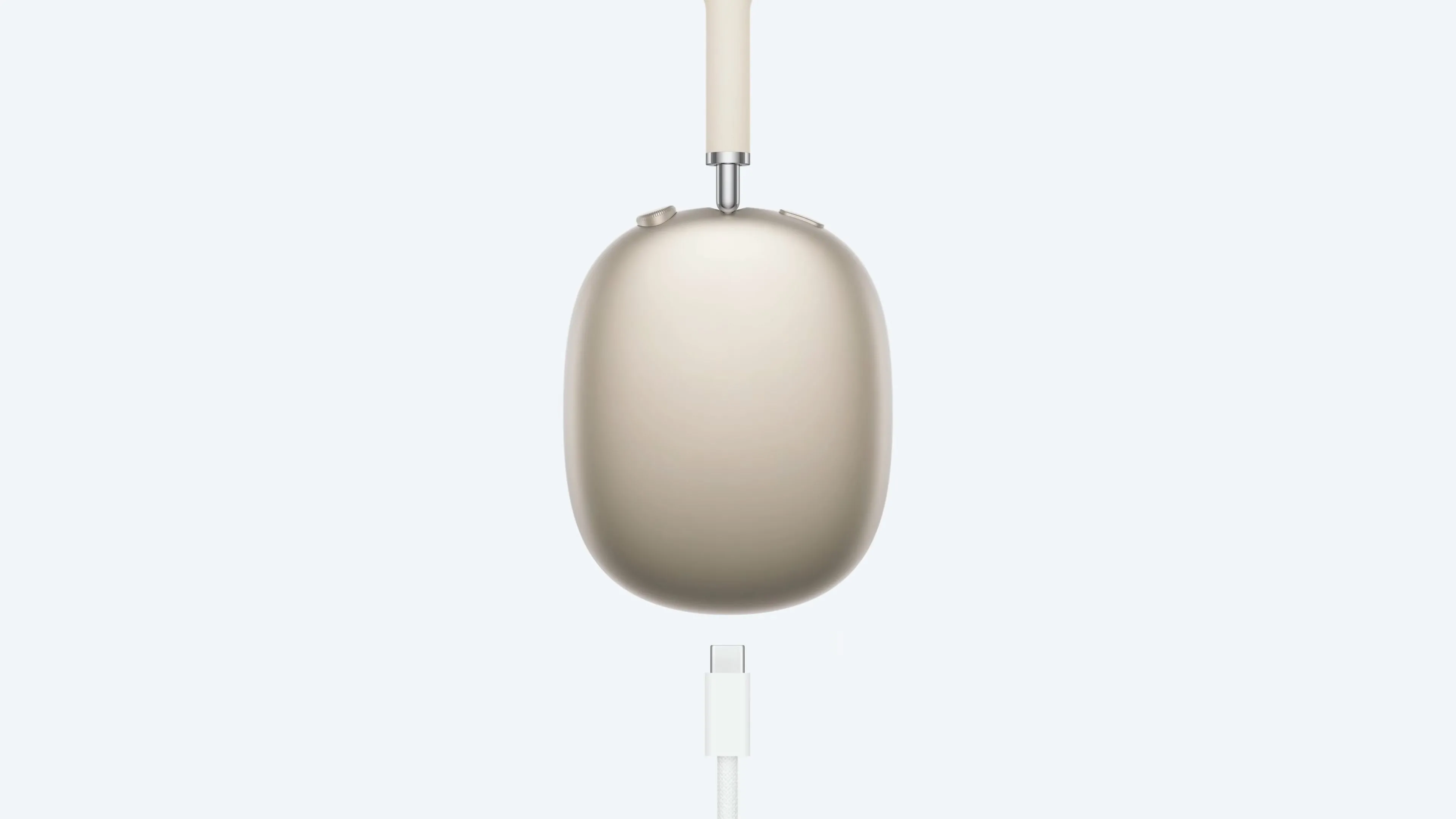Tai nghe AirPods Max màu Starlight đang sạc qua cáp USB-C, minh họa hạn chế không thể vừa sạc vừa nghe.