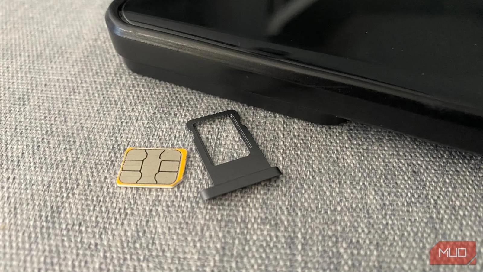 Thẻ SIM vật lý và khay đựng bên cạnh điện thoại di động trên bàn