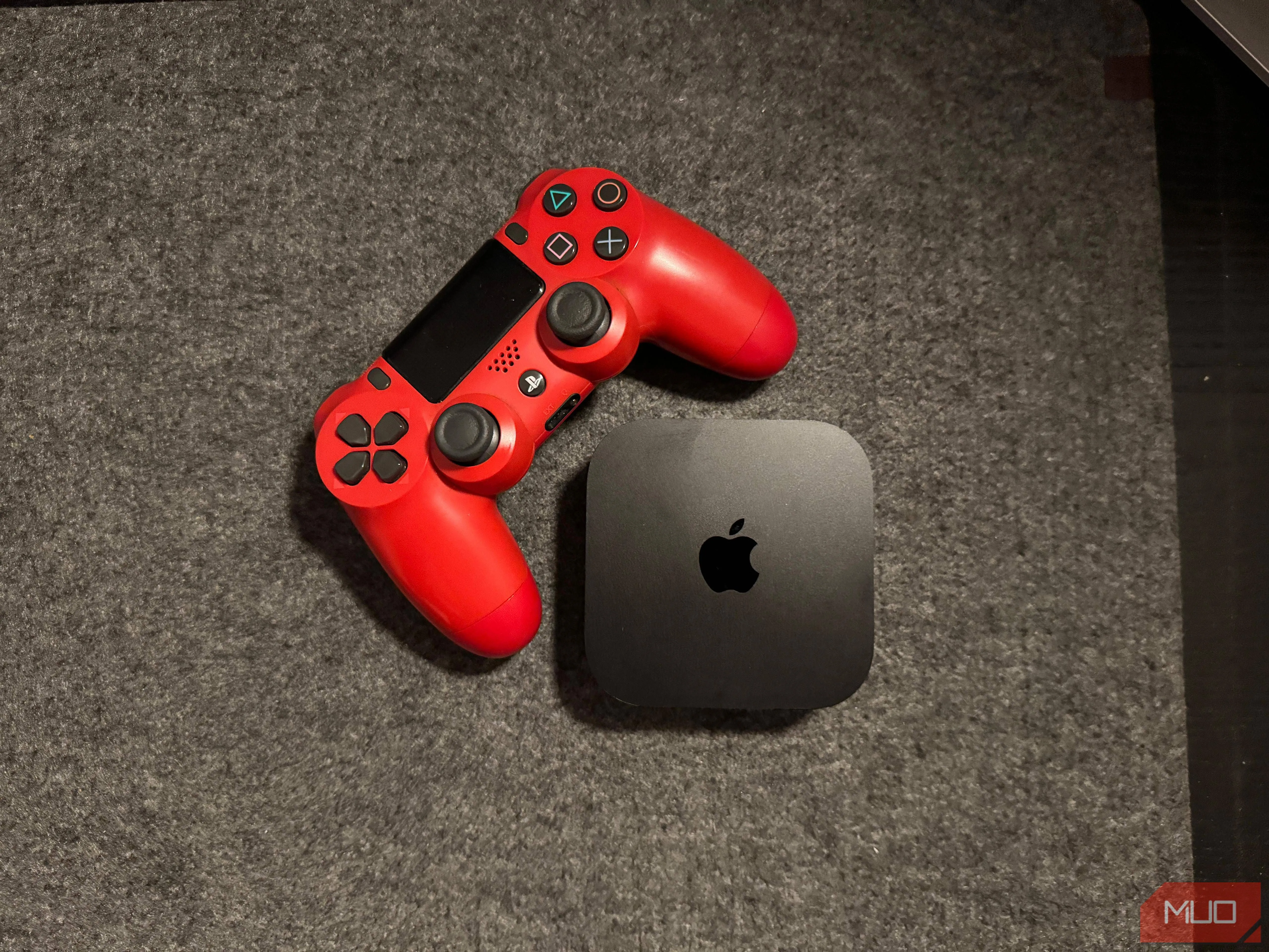 Thiết bị Apple TV 4K đặt cạnh tay cầm chơi game PS4, minh họa khả năng kết nối và chơi game trên nền tảng tvOS.