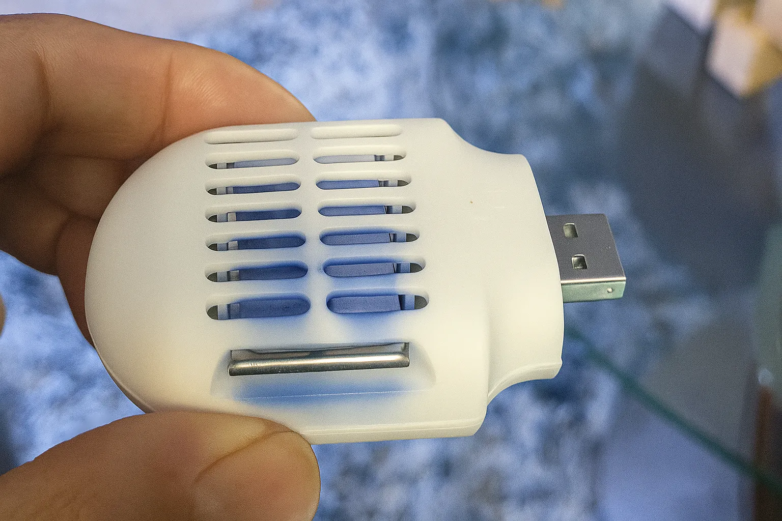 Thiết bị chống muỗi cắm USB Moskiller nhỏ gọn màu trắng được giữ trong lòng bàn tay, phù hợp dùng trong ô tô